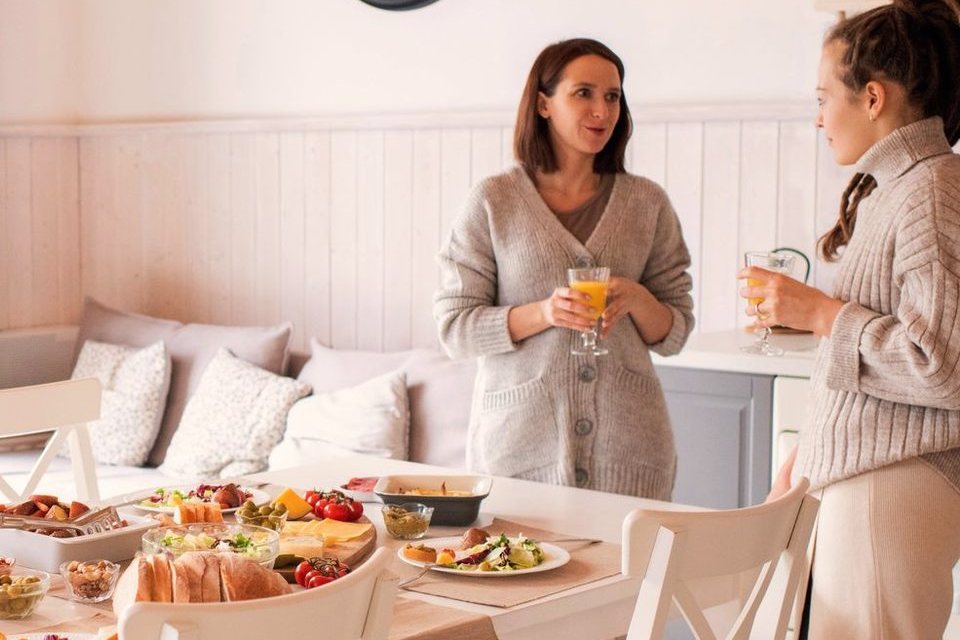 Two women in conversation over a table laid with food
